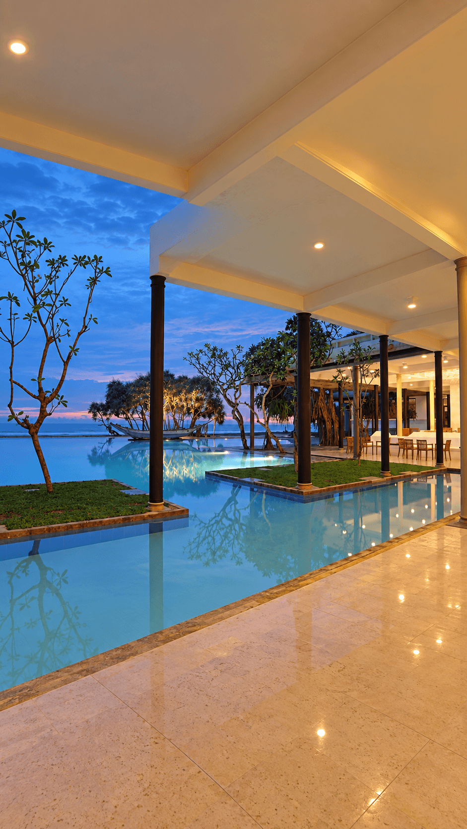 A beachfront pool and pavilion overlooking the ocean at dusk
